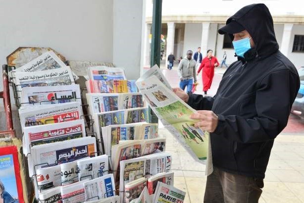 lector con mascarilla leyendo un diario en la calle